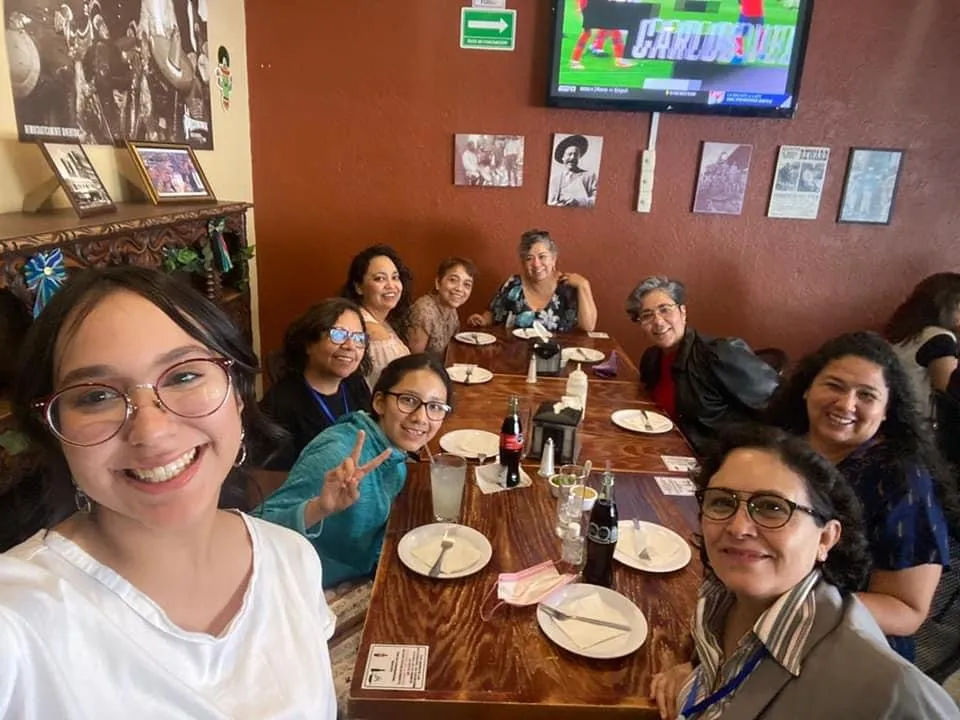 Lili con mujeres de un círculo, compartiendo la mesa